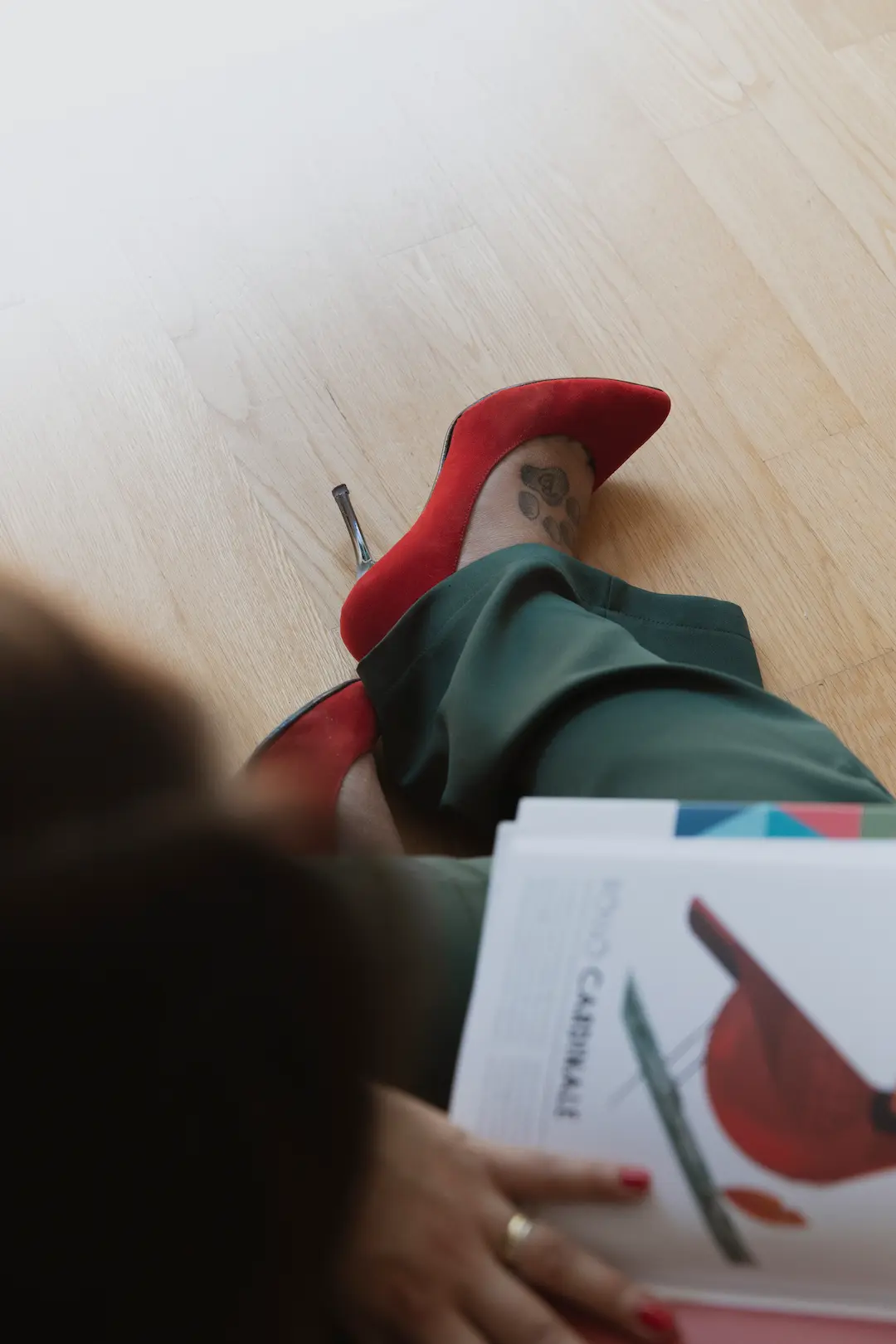 ragazza seduta sul parquet mentre sfoglia una rivista